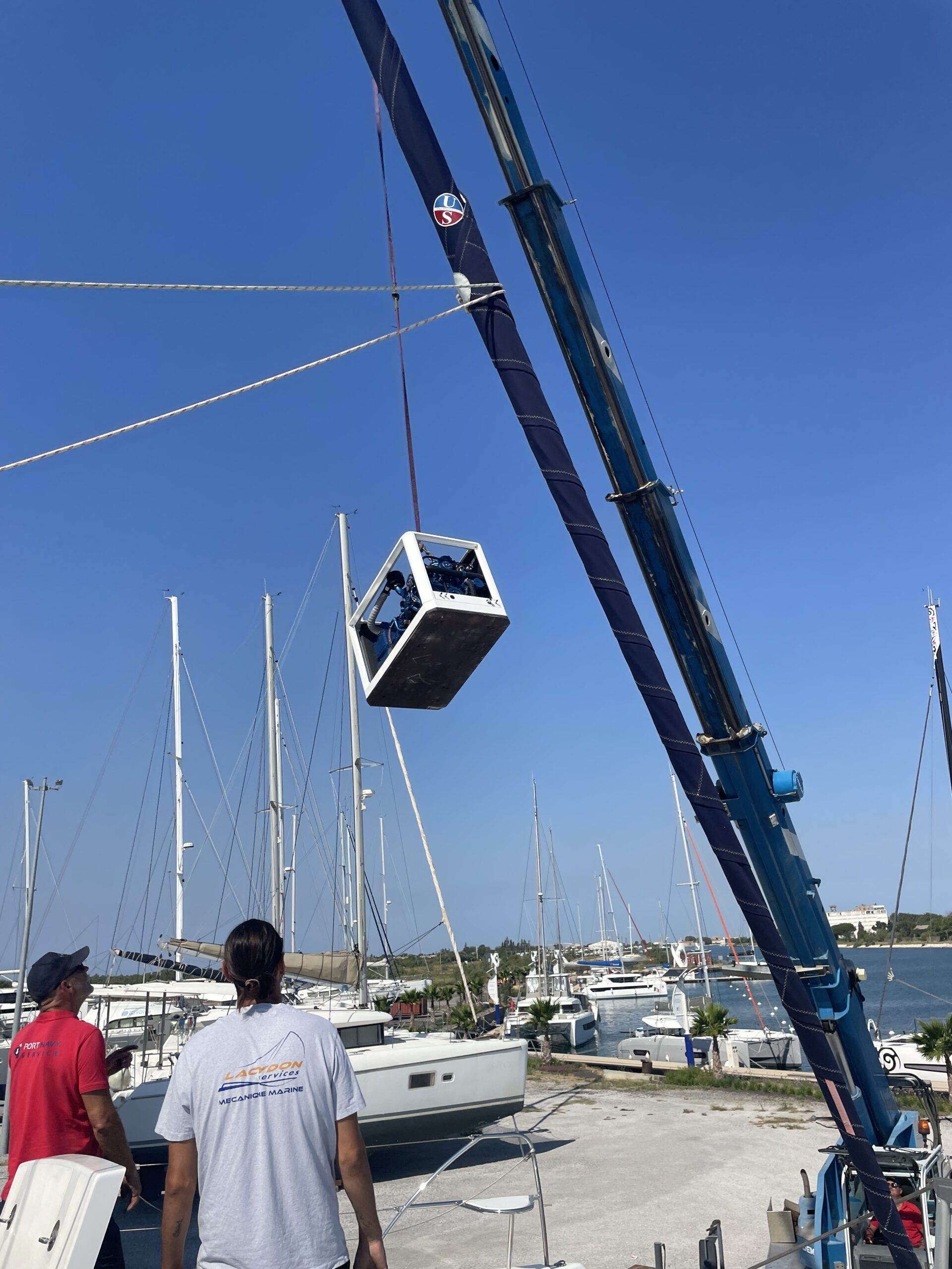 Grue levant un voilier dans un port de plaisance